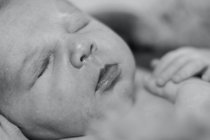 Serene close-up of sleeping newborn in black and white.