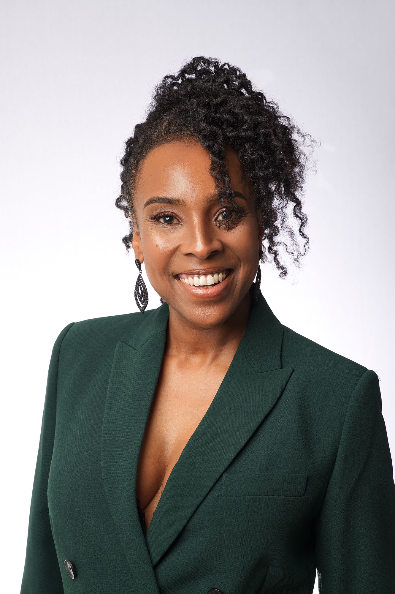 Studio portrait in emerald green blazer against light background.