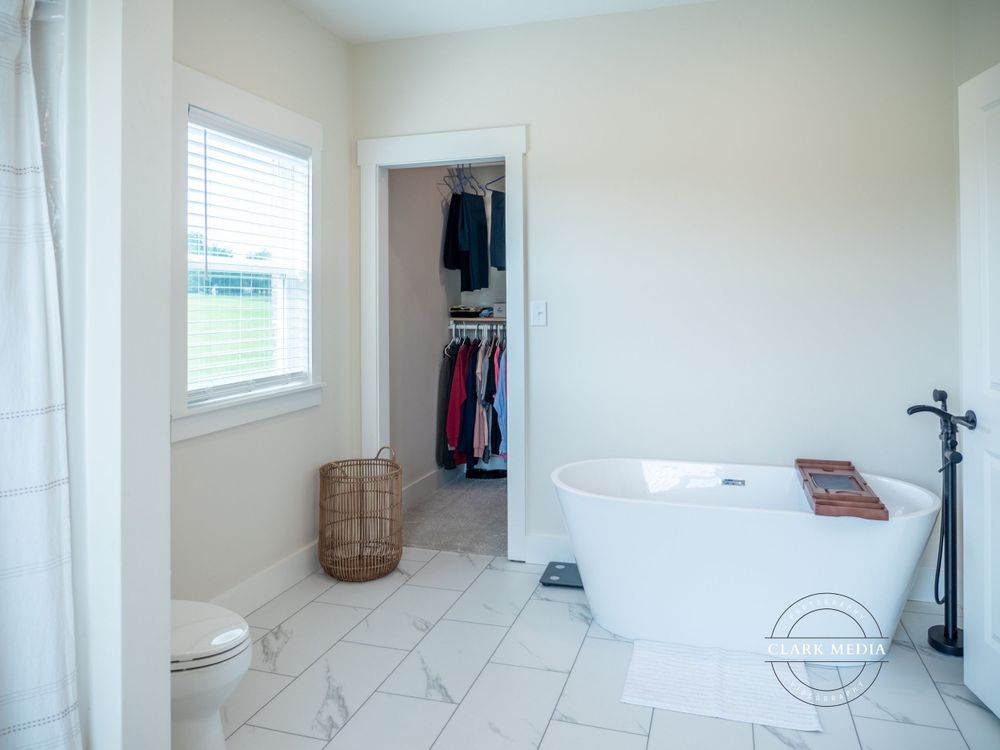 Modern bathroom with white bathtub, wicker basket, and built-in closet space.