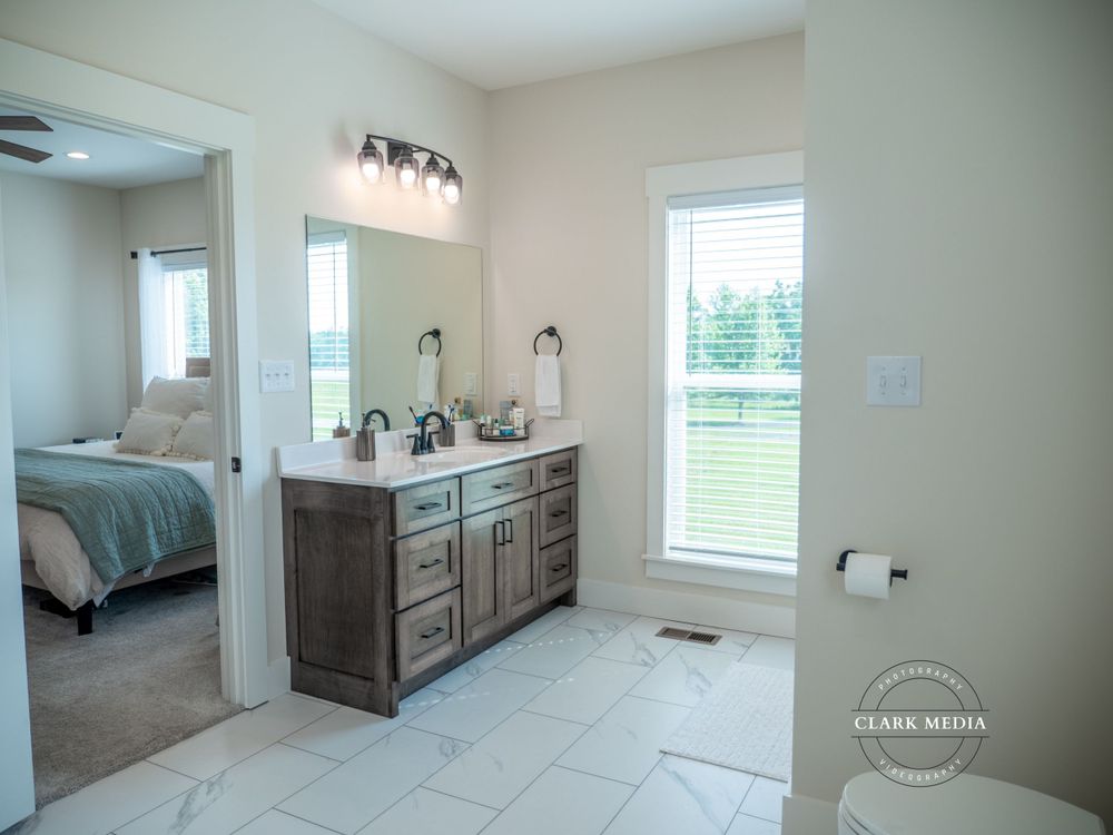Spacious bathroom featuring double vanity with wooden cabinets and tiled flooring.
