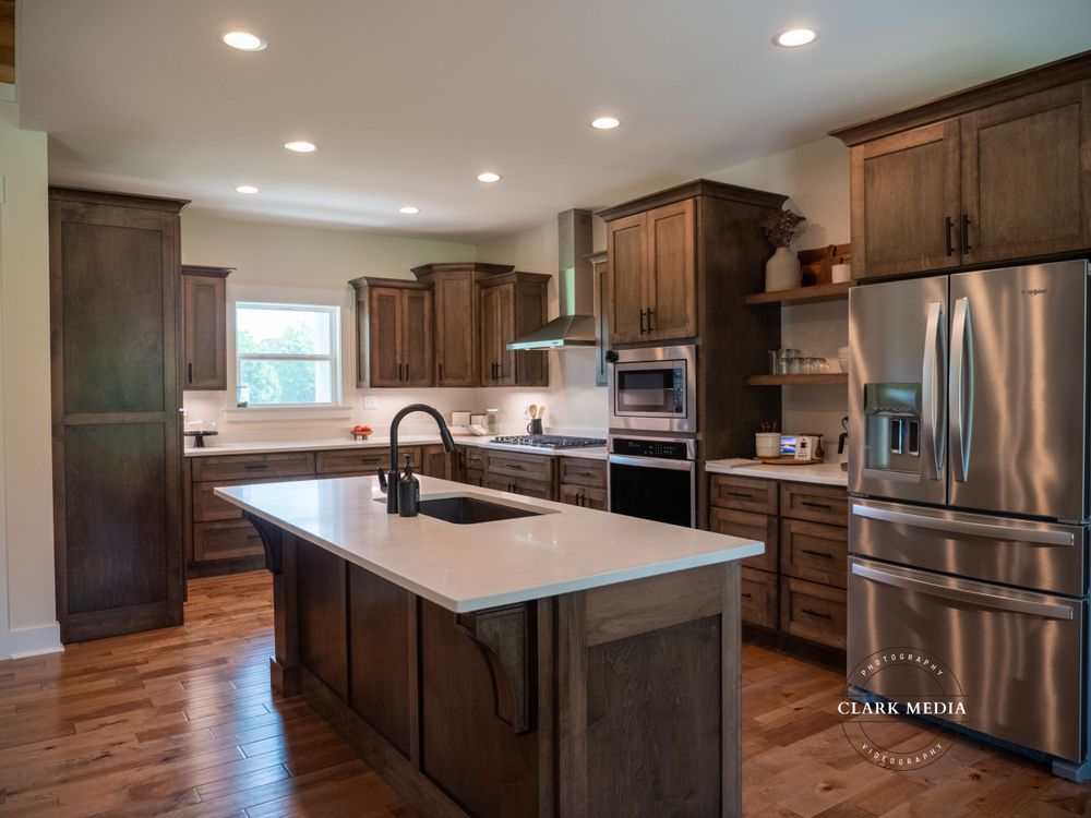 Modern kitchen with dark wood cabinets, white countertops, and stainless steel appliances.