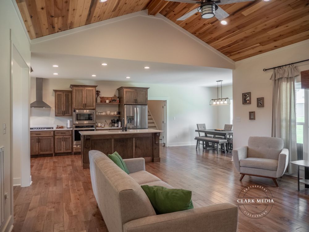 Open floor plan living area with wood ceiling, modern kitchen, and comfortable seating.