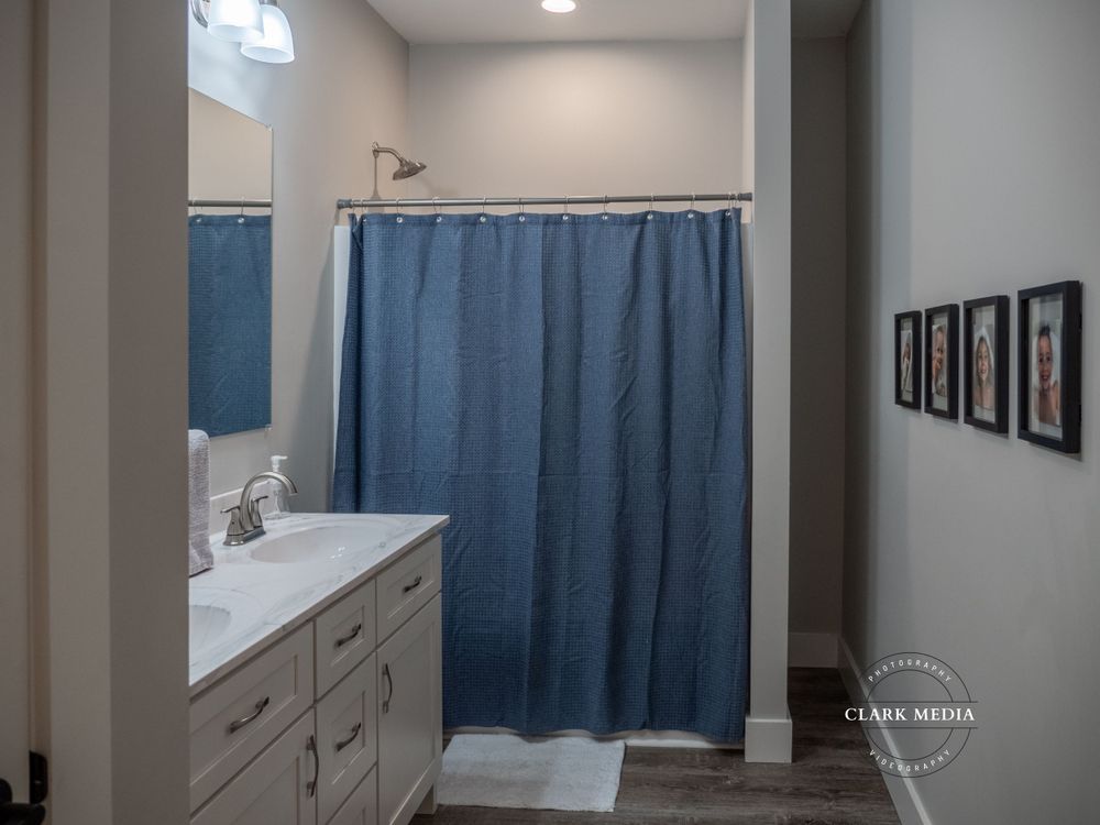 Modern bathroom with vanity, blue shower curtain, and framed wall art.