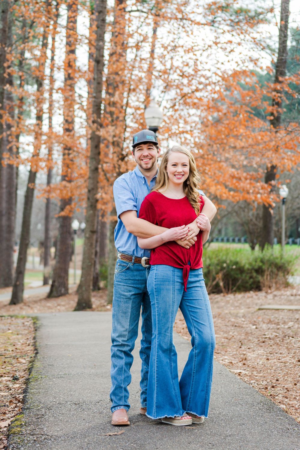 Couple embracing on path with fall foliage in background.