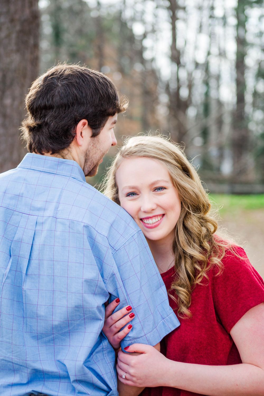 A couple in red and blue attire sharing a romantic moment outdoors.