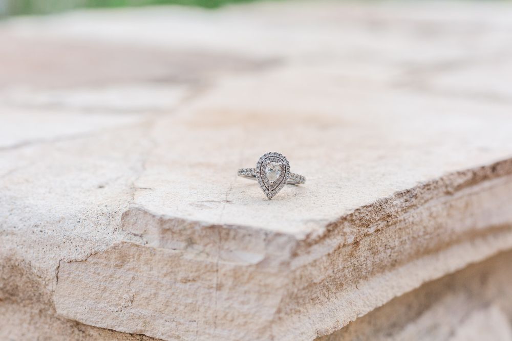 Elegant pear-shaped diamond ring on textured stone surface.
