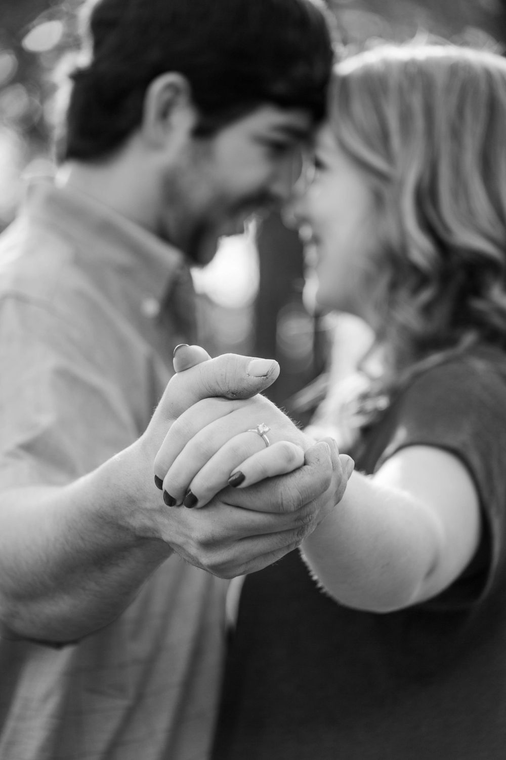 Black and white intimate portrait of a couple holding hands while sharing a tender moment.