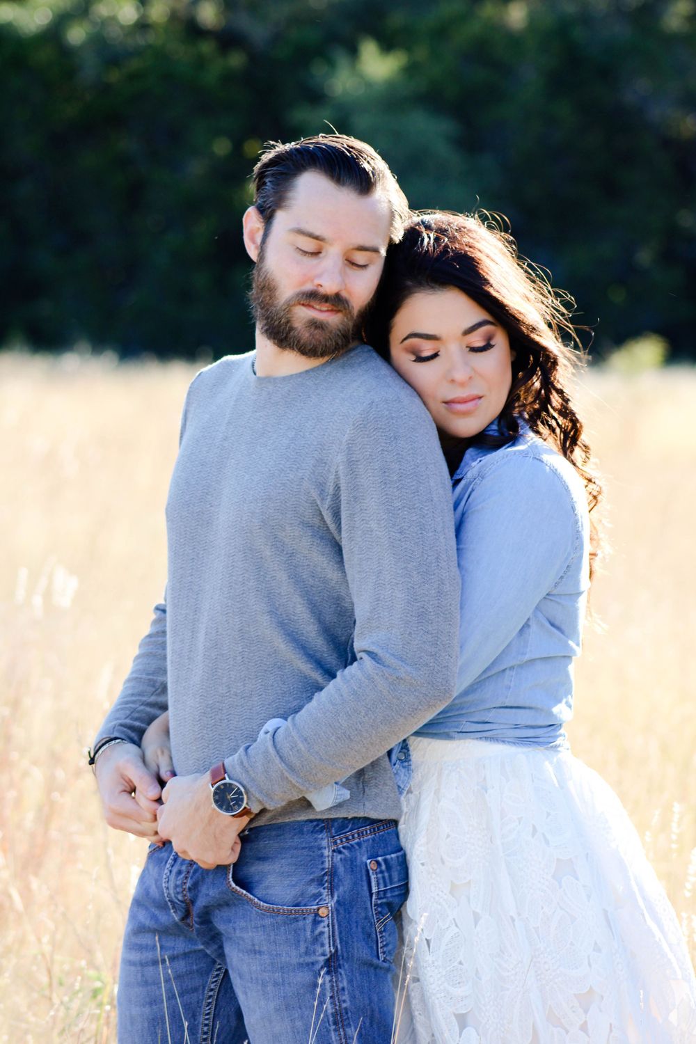 Romantic couple embraces in golden field during sunset photoshoot.