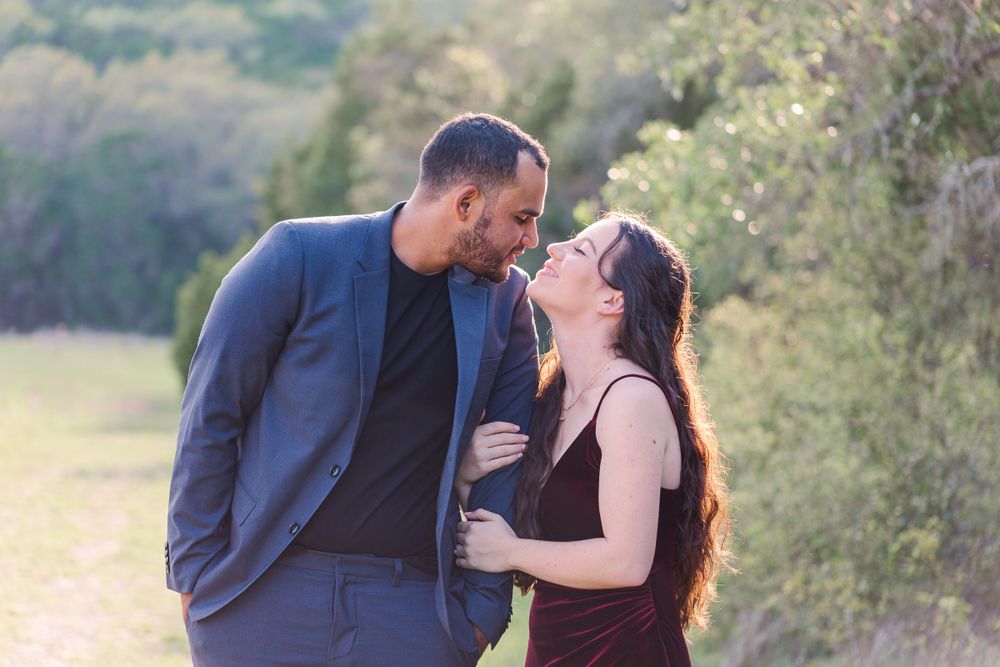 Couple shares intimate moment outdoors against nature backdrop.