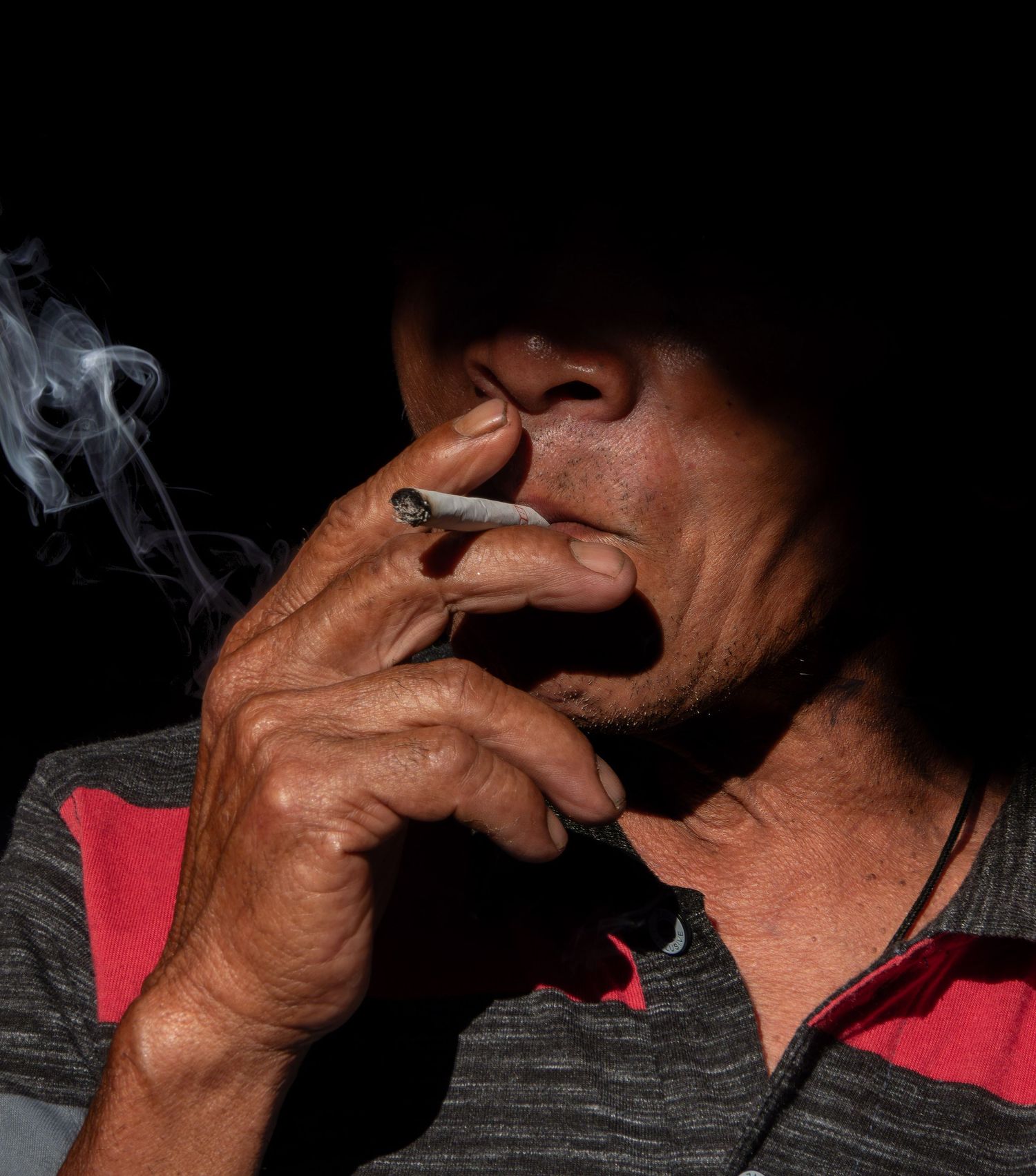 Dramatic close-up shot of smoke rising from cigarette in dark lighting.