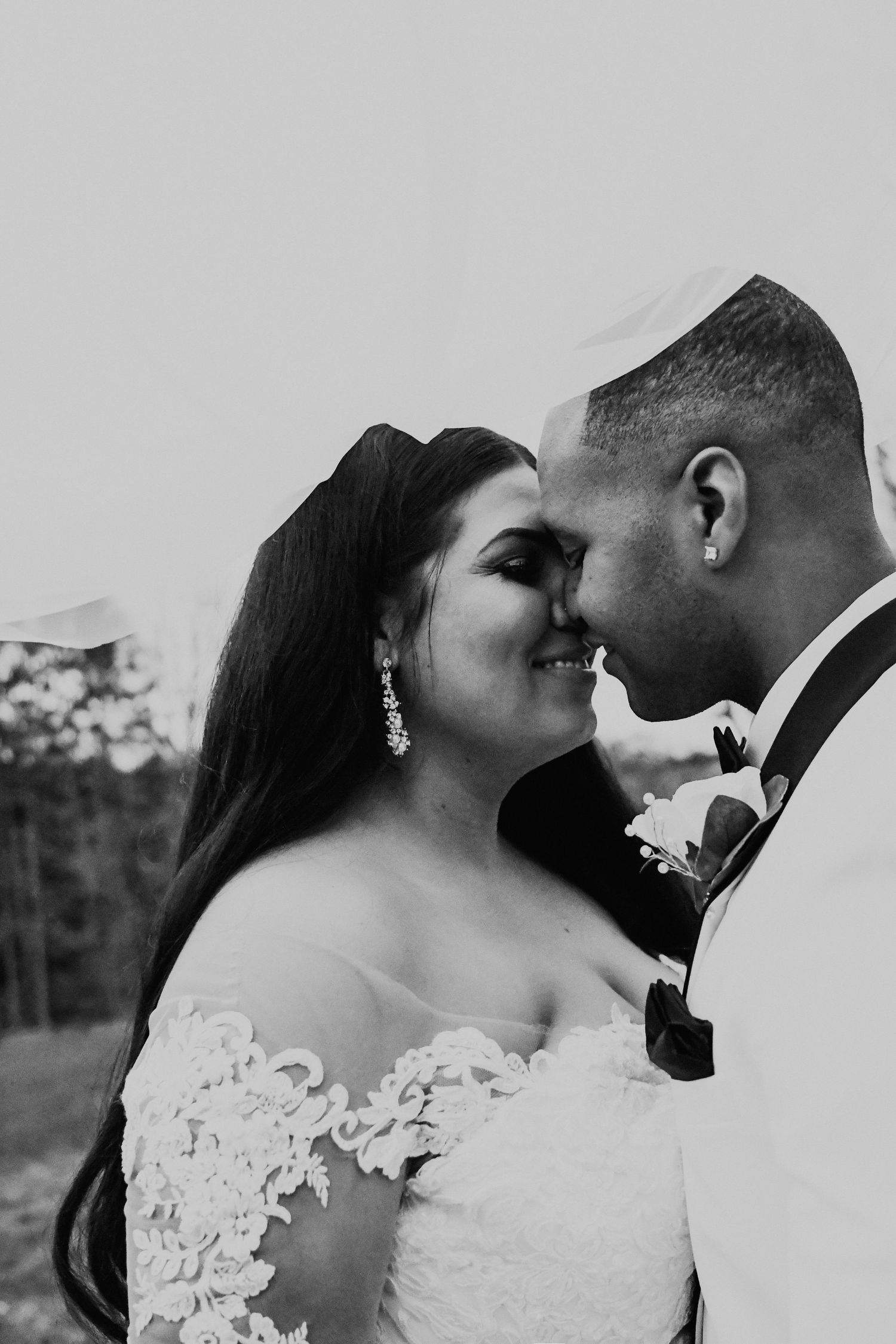 A romantic black and white wedding portrait showing an intimate moment between newlyweds.