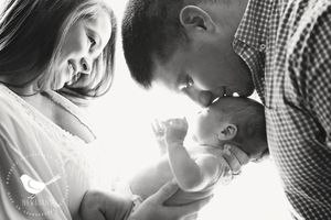 Black and white portrait of family moment backlit by soft window light.