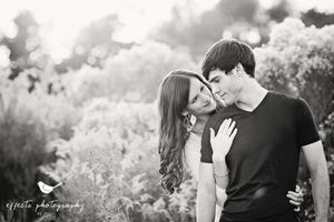 Black and white romantic portrait of couple sharing intimate moment in dreamy outdoor setting.