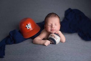 Newborn photography with Houston Astros baseball theme on grey background.