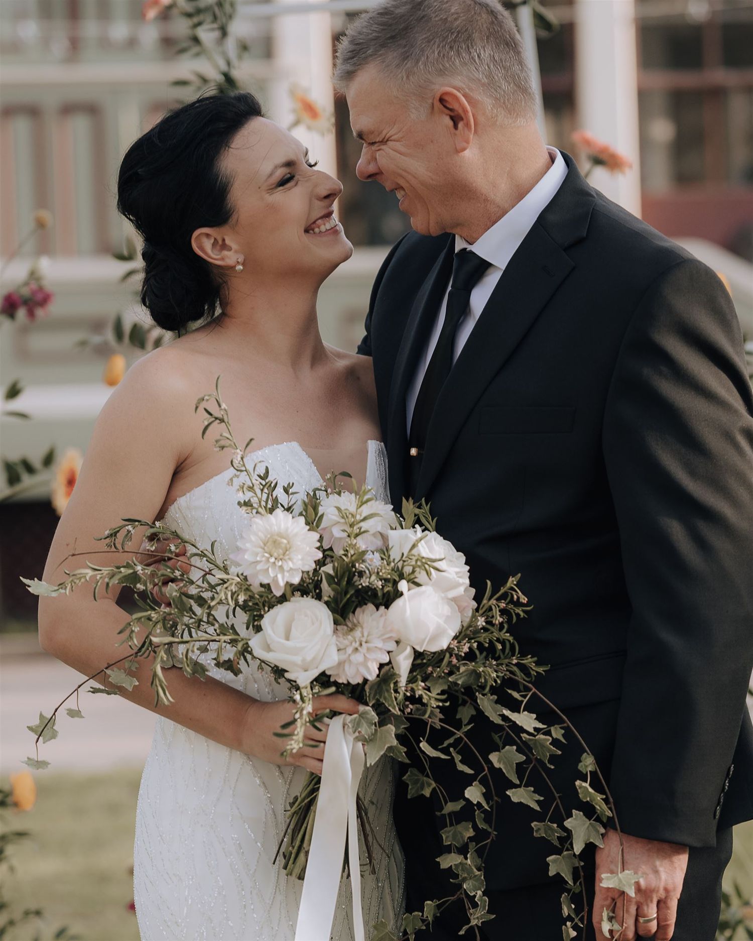 Romantic moment between couple with elegant white floral bouquet at outdoor wedding.