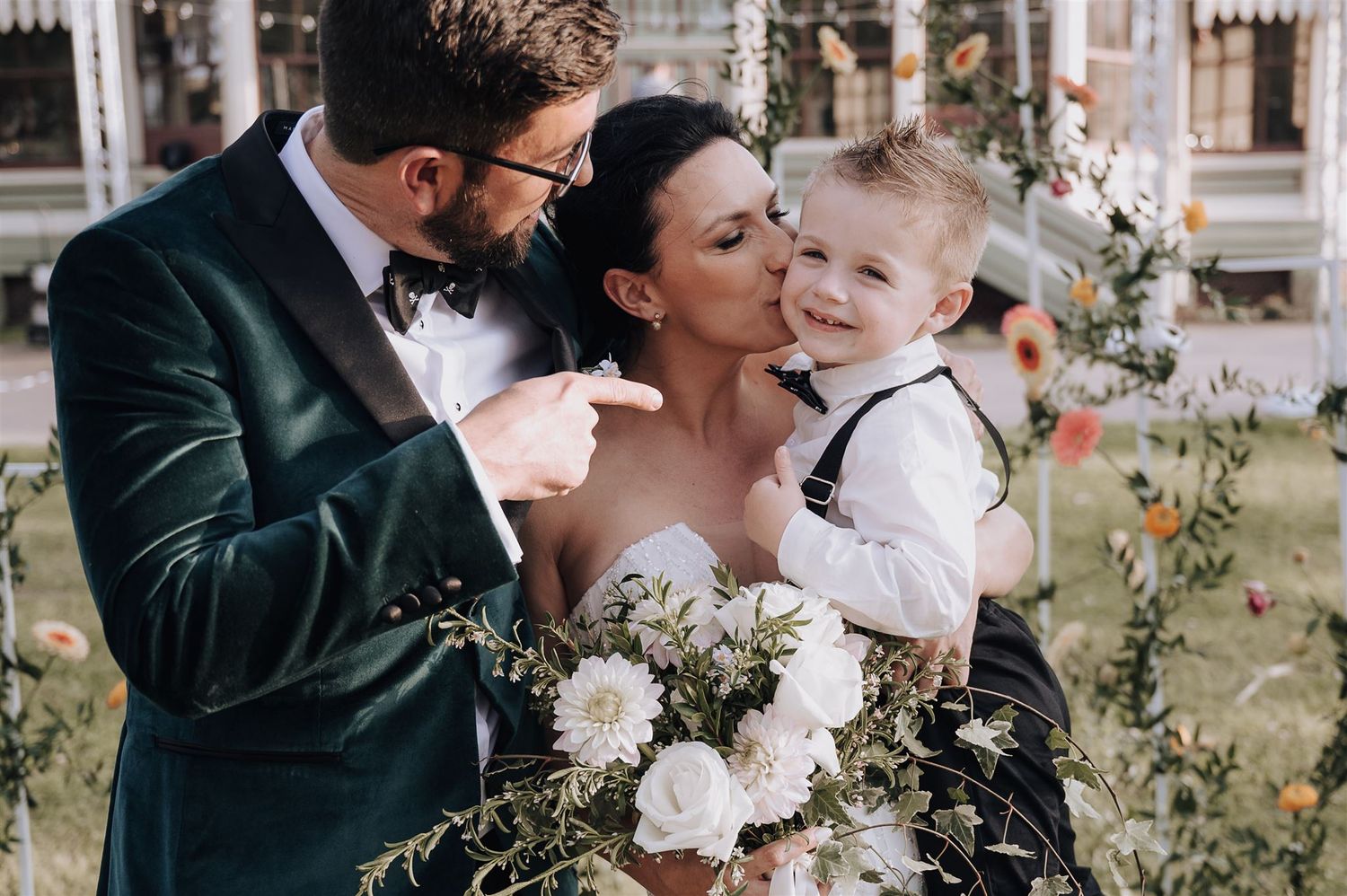 Tender family moment captured during wedding with elegant floral arrangements.