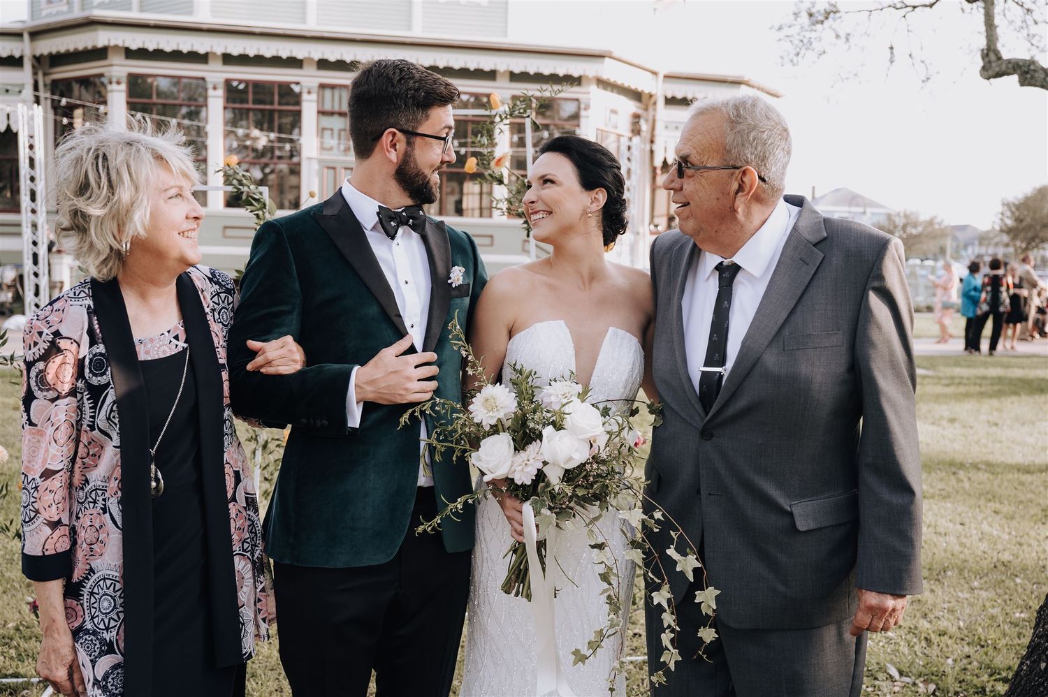 Intimate moment shared between wedding couple and family members in outdoor garden setting.