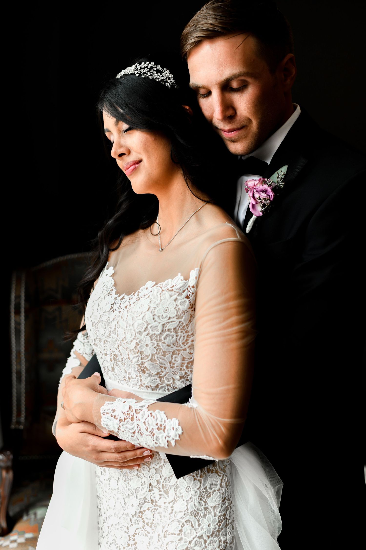 Romantic wedding portraits in dramatic low-key lighting with lace dress details.