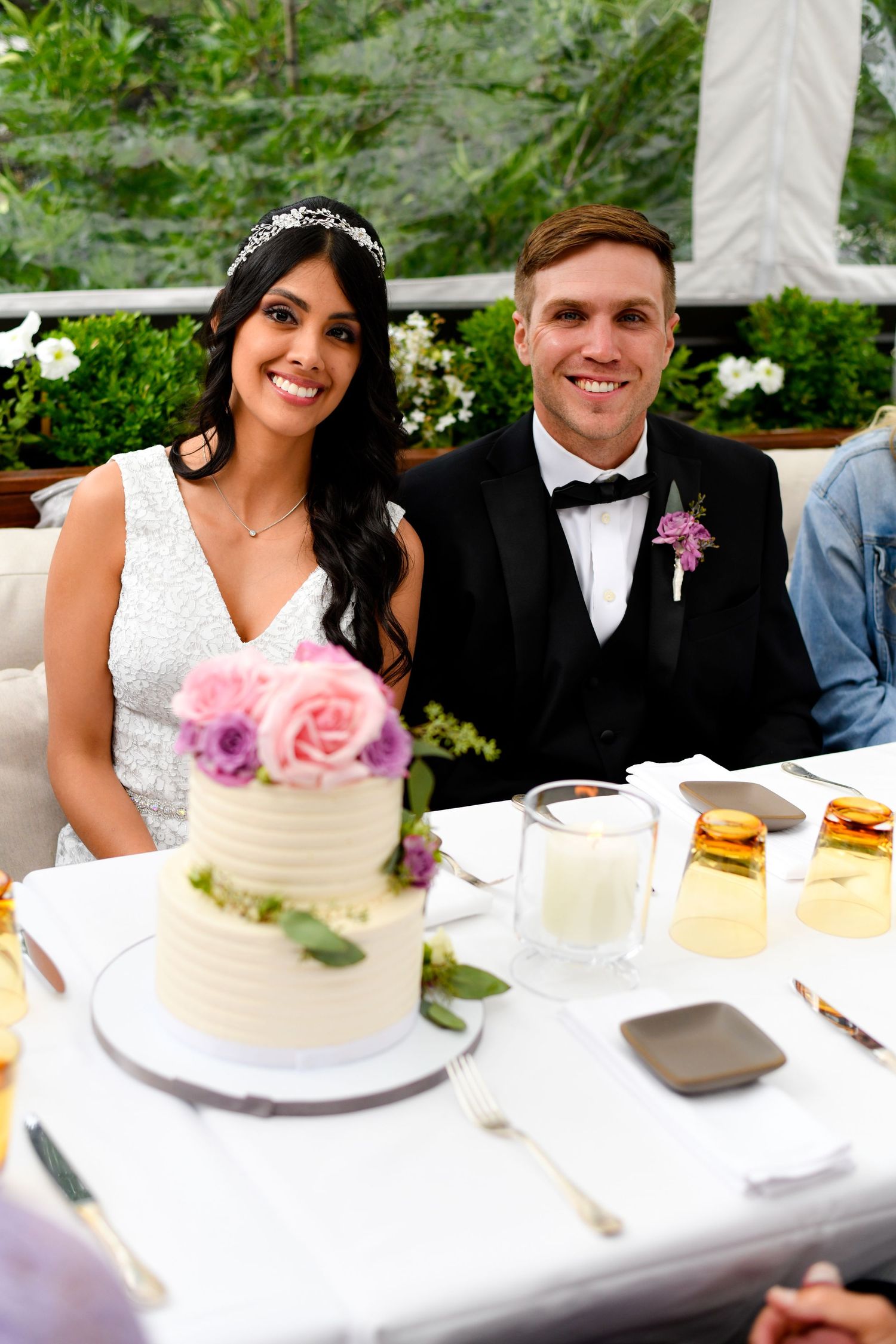 A wedding reception table scene with cake and newlyweds.