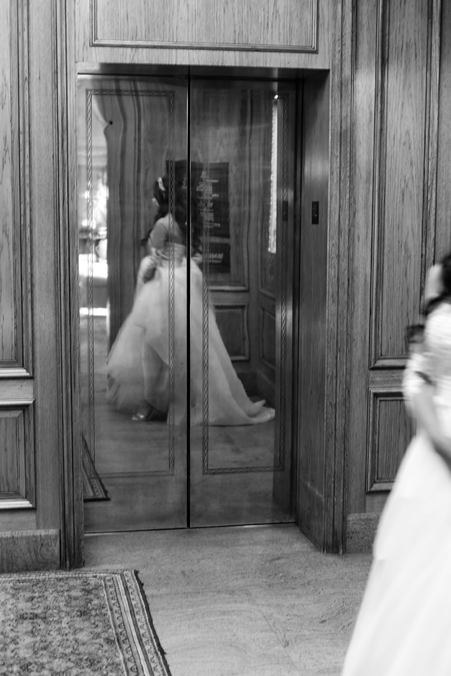 Motion blur sequence of figures in white dresses moving through wood-paneled hallway.