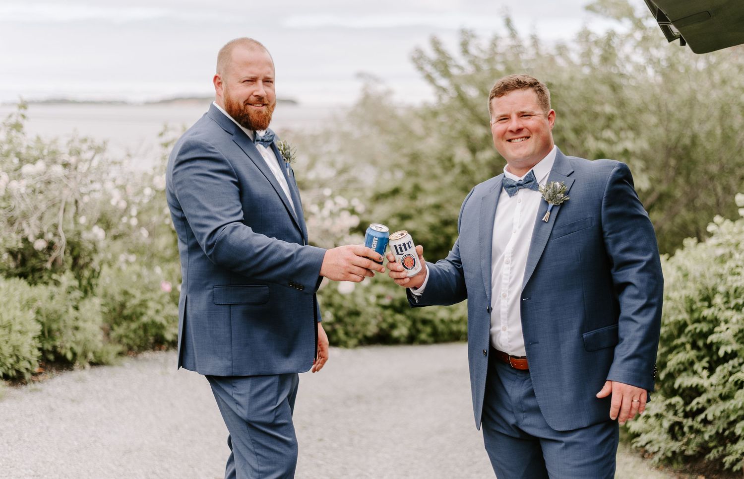 Groomsmen in navy suits share candid moments in garden setting.
