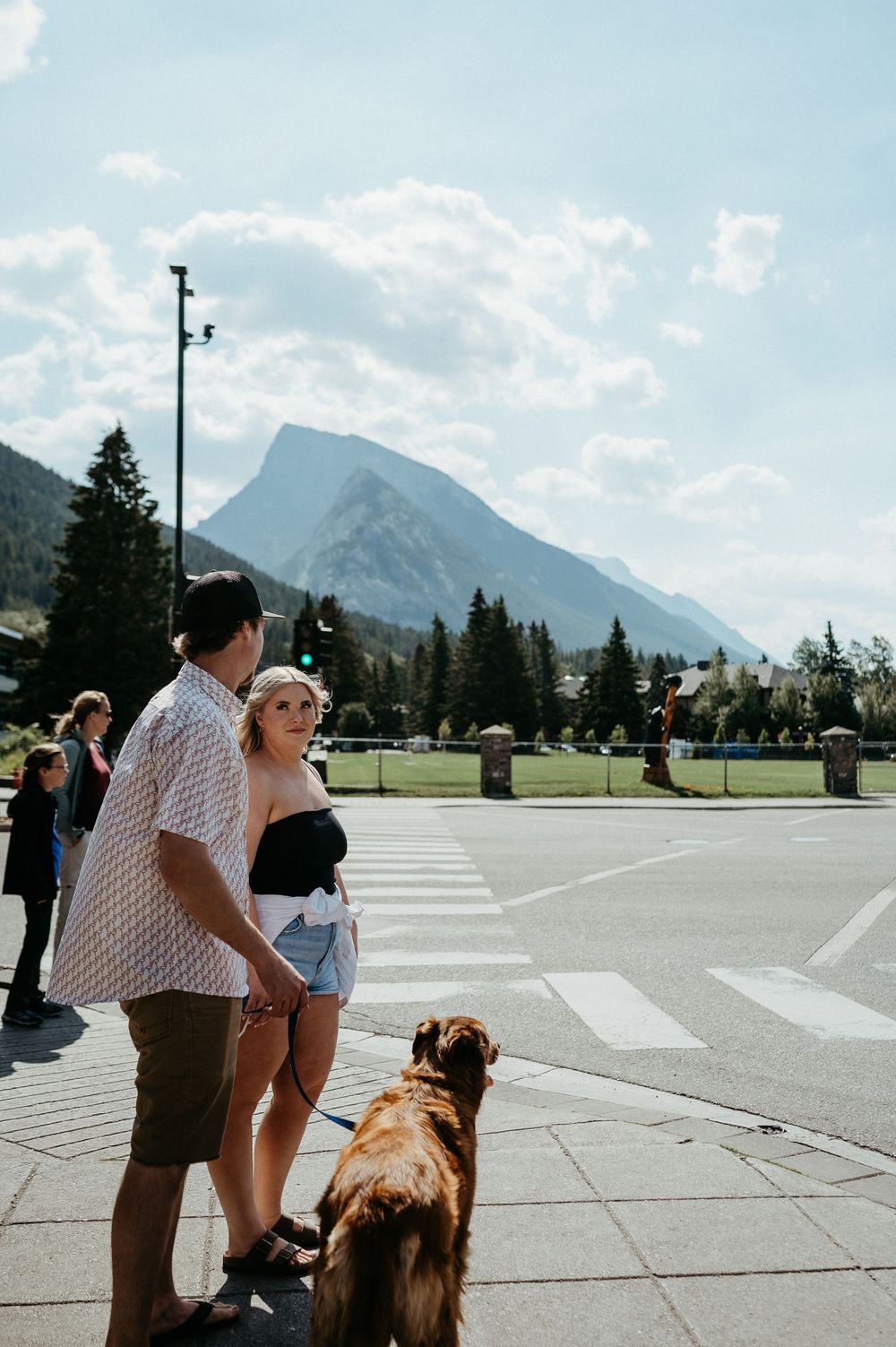 Tourists with their dog enjoying a mountain view in a town square on a sunny day.
