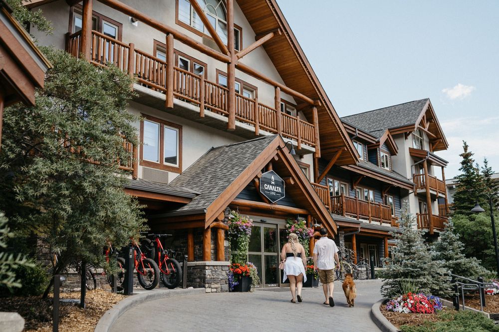 Rustic mountain lodge with wooden balconies and bikes parked outside.