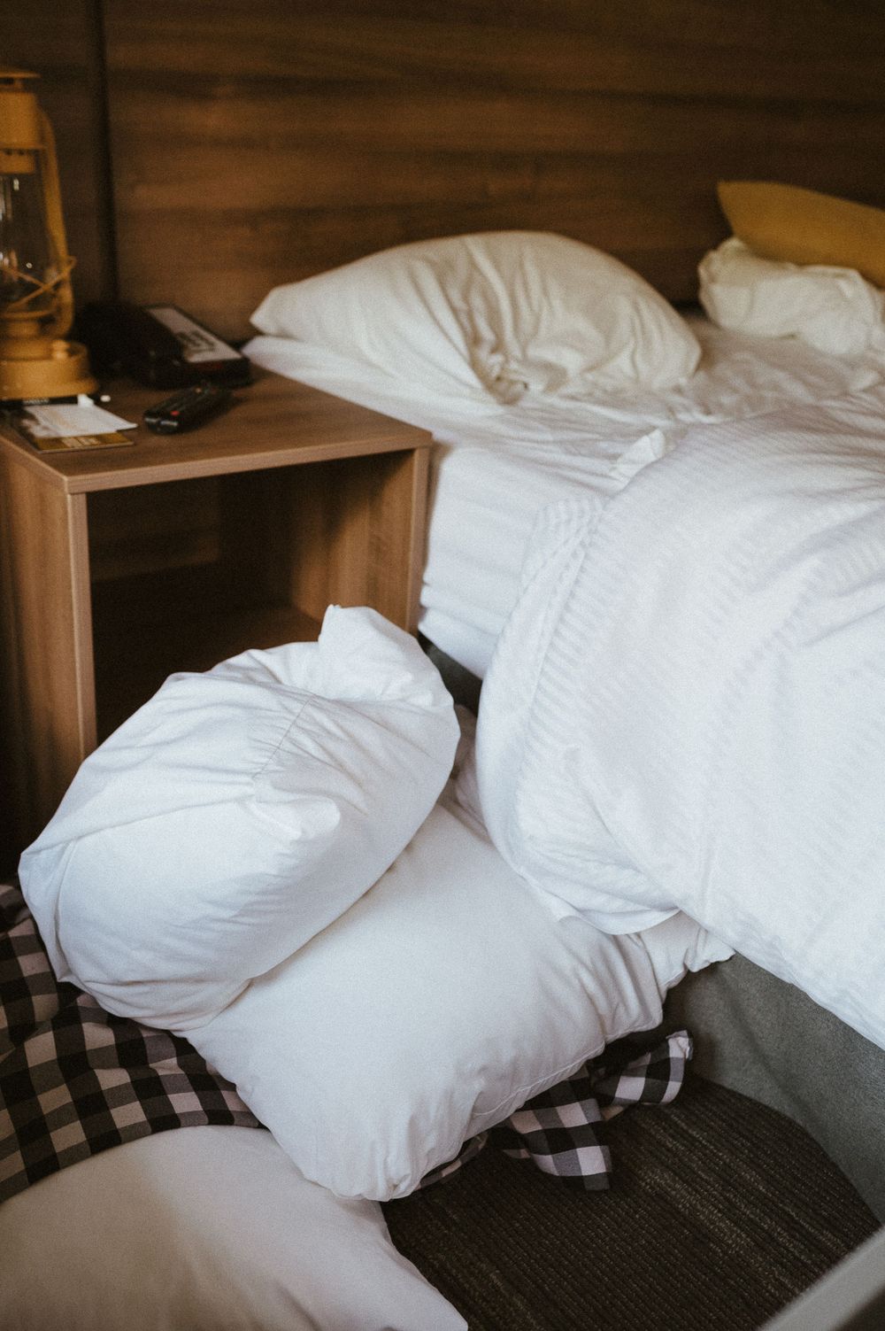Cozy unmade bed with white pillows and bedding in a rustic cabin setting.