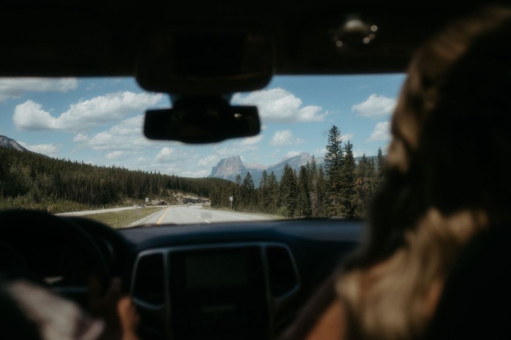 Mountain landscape viewed through car windshield while driving on scenic road.