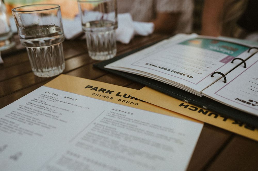 Restaurant menu and water glasses on wooden table at Park Life Cafe.