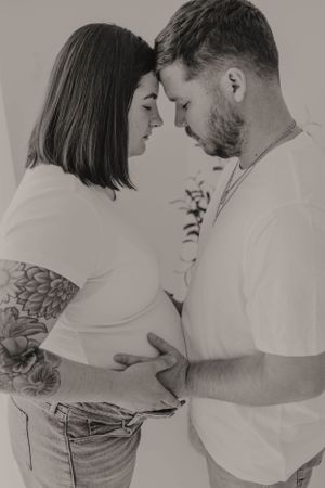 A romantic black and white photo of an expecting couple sharing an intimate moment together.