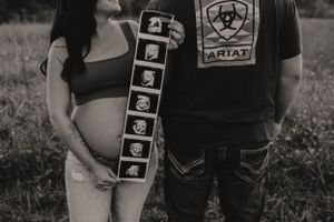 Black and white photo showing a strip of ultrasound images next to an expecting mother and partner.
