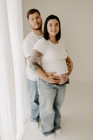 Maternity portrait in minimalist white studio setting.