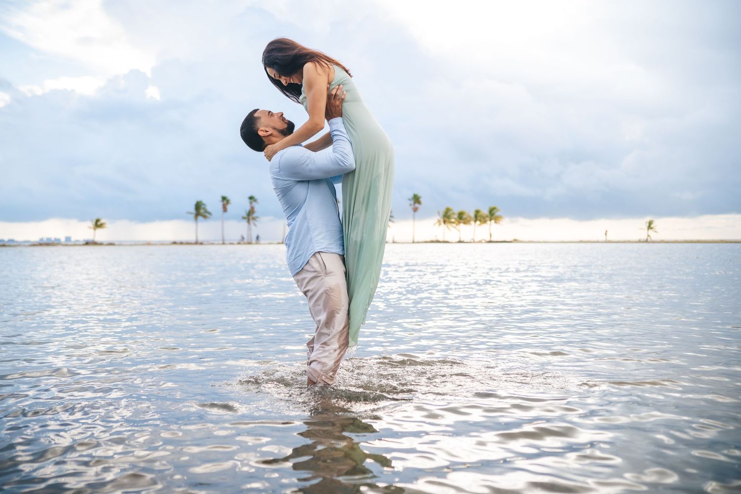 Romantic couple embracing in shallow tropical waters during sunset.