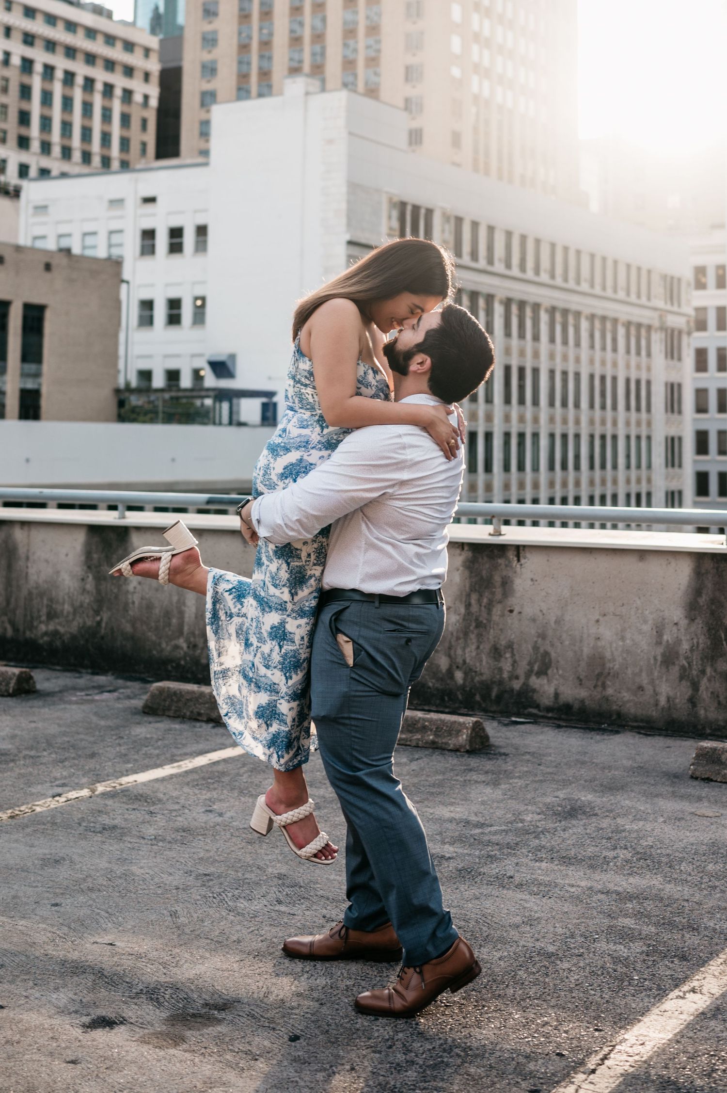 A couple shares a playful lift moment on an urban rooftop.