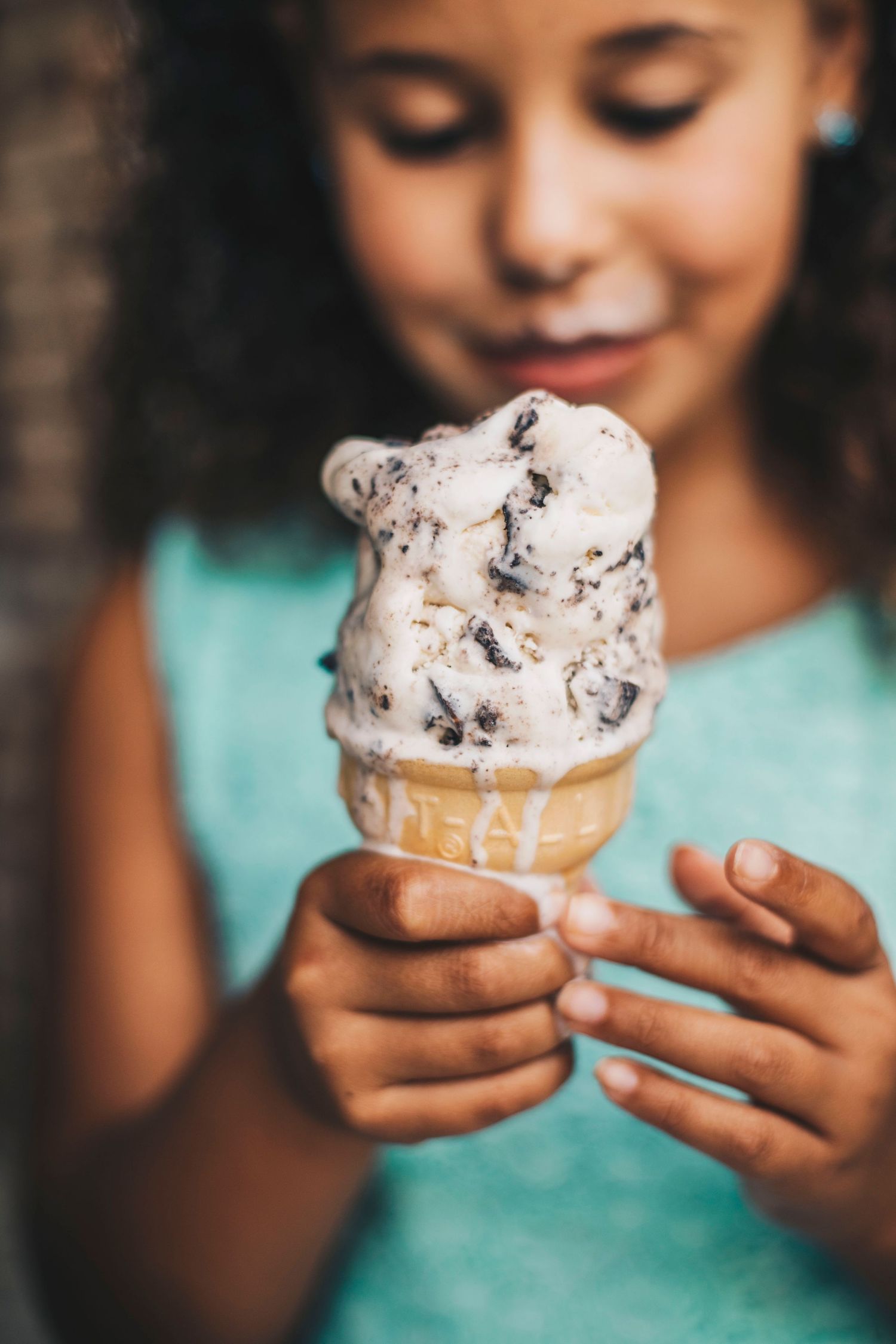 Young girl holding a cookies and cream ice cream cone in a waffle cone.