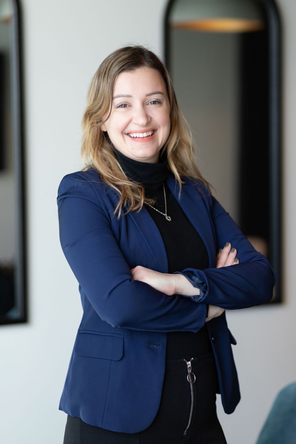 Business professional poses in a navy blazer in an office setting.
