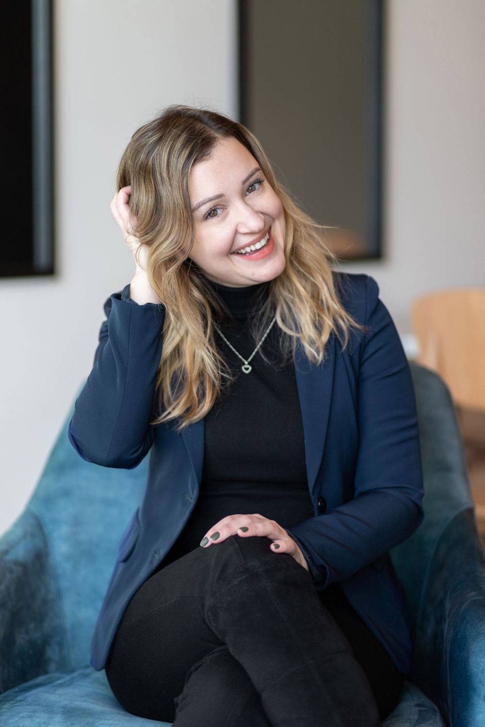 Casual business portraits on a blue couch wearing a navy blazer.