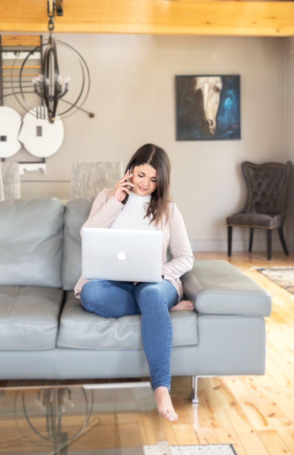 Person relaxing on gray couch with laptop in casual home setting.