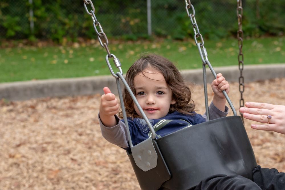 A child giving the "thumbs-up" while swinging