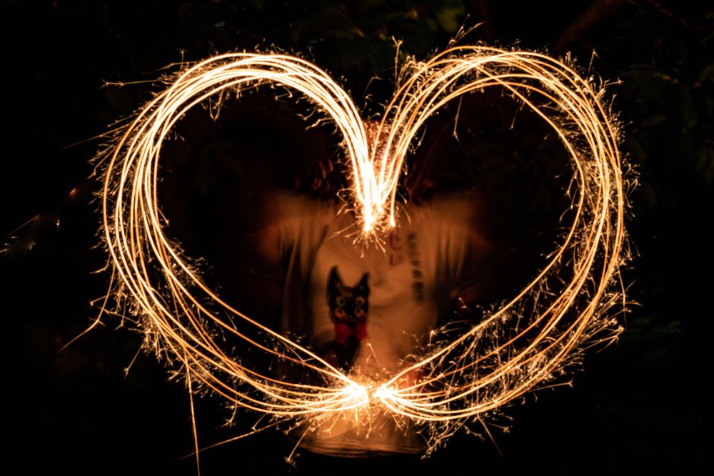 A woman making a heart design out of light trails