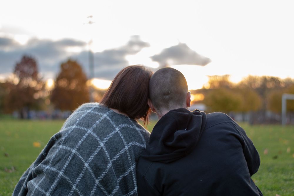 A couple leaning in close to watch the sun set