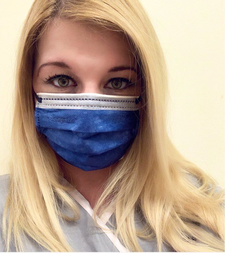 Healthcare worker wearing a blue surgical face mask and white uniform.