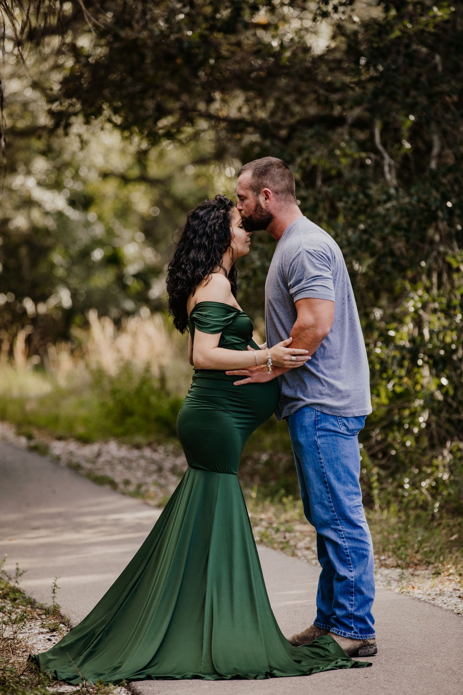 Couple embracing outdoors, with person wearing flowing emerald green dress.