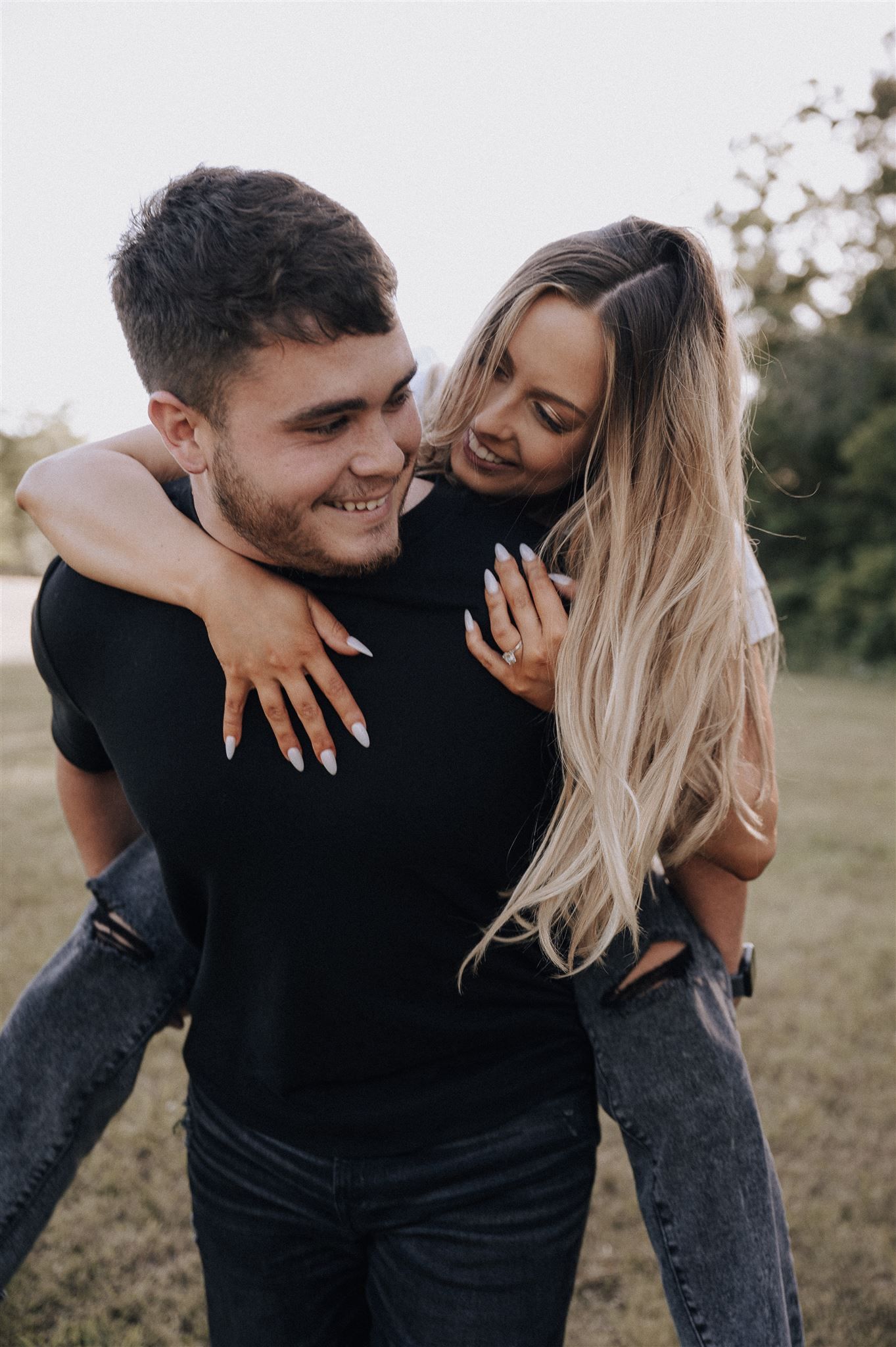 Happy couple enjoying a piggyback ride moment in a grassy field.
