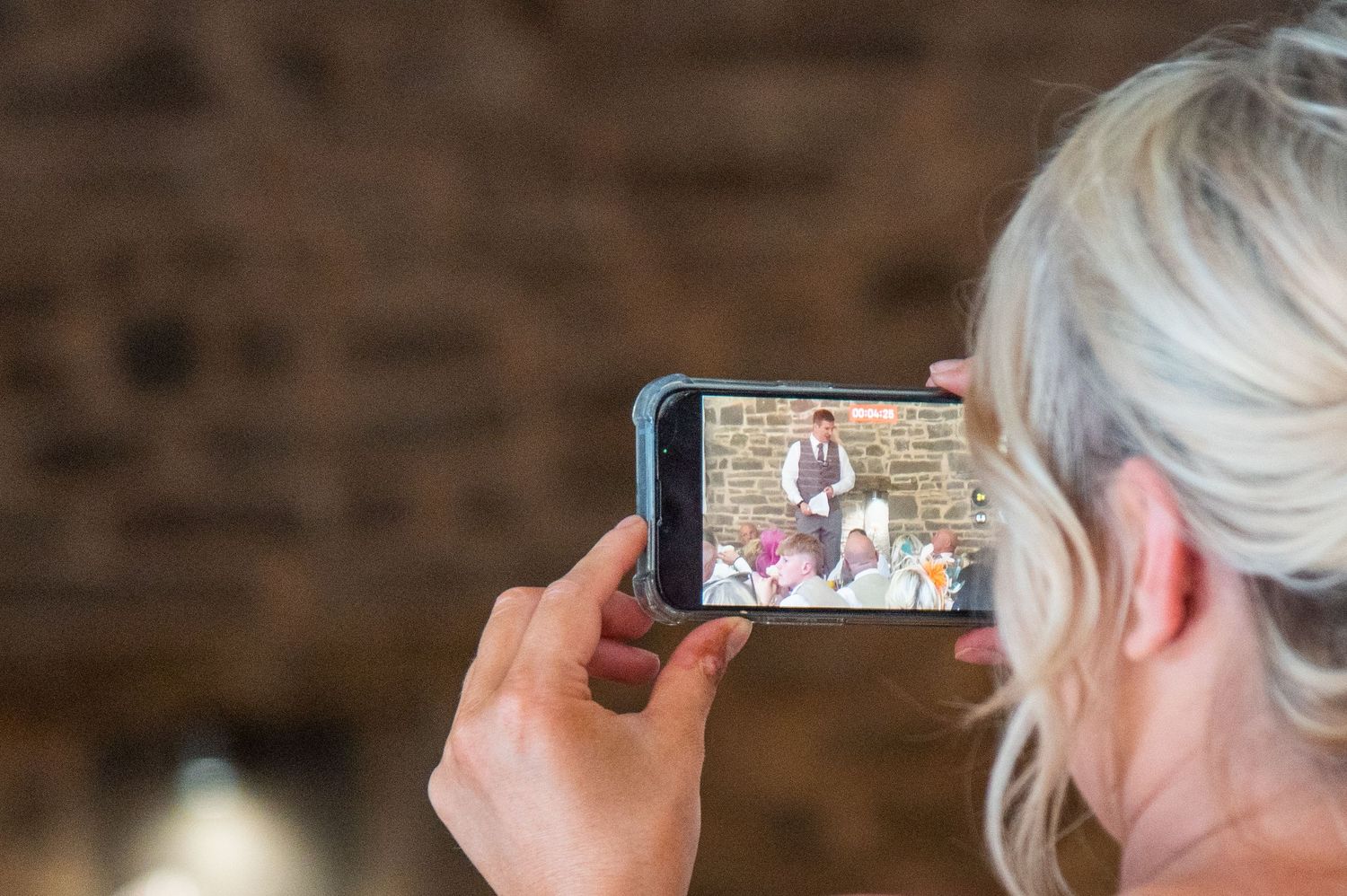 Guest capturing wedding moments on mobile phones at reception venue.