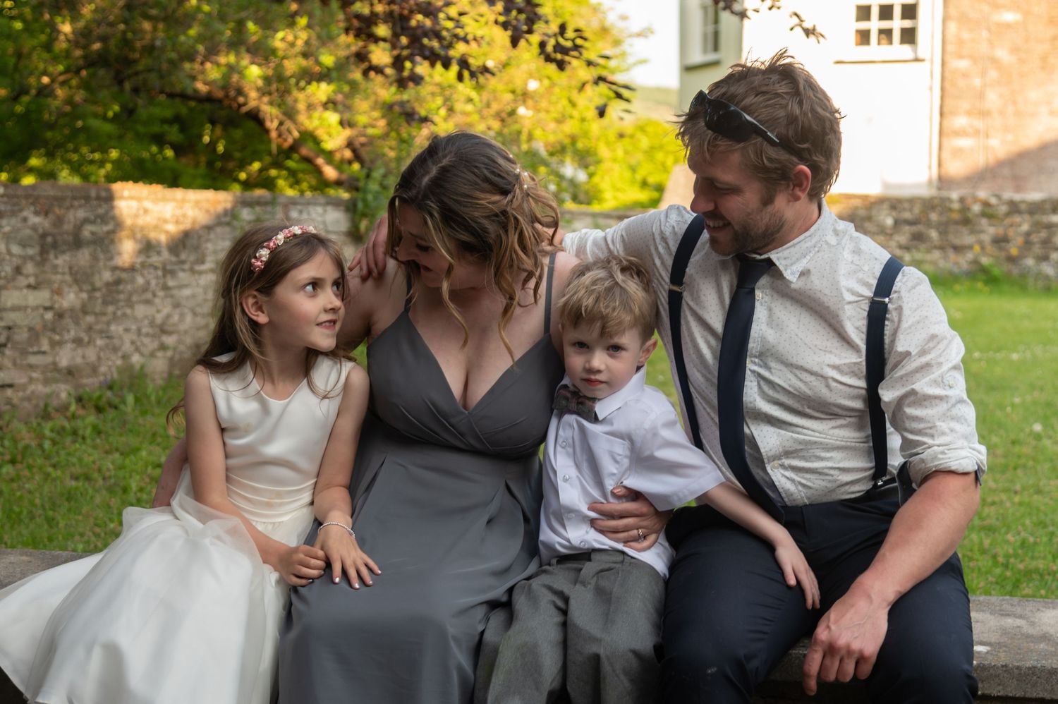Wedding party enjoying candid moments outdoors in a garden setting.