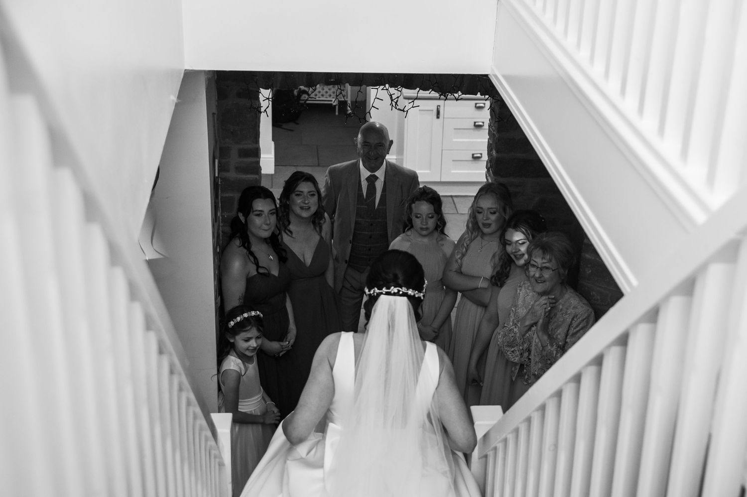 Wedding guests descending a white staircase in formal attire.