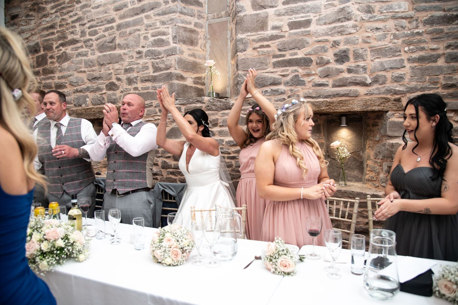Wedding guests laughing and enjoying speeches during a reception celebration at stone venue.