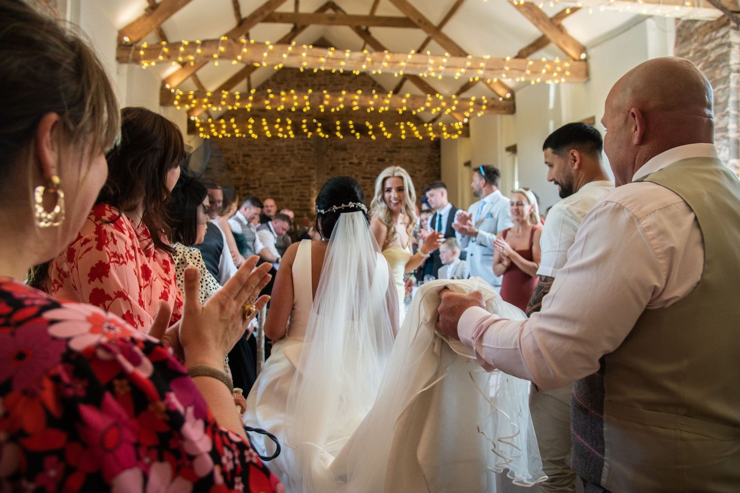Wedding reception venue decorated with hanging lights and rustic wooden beams.